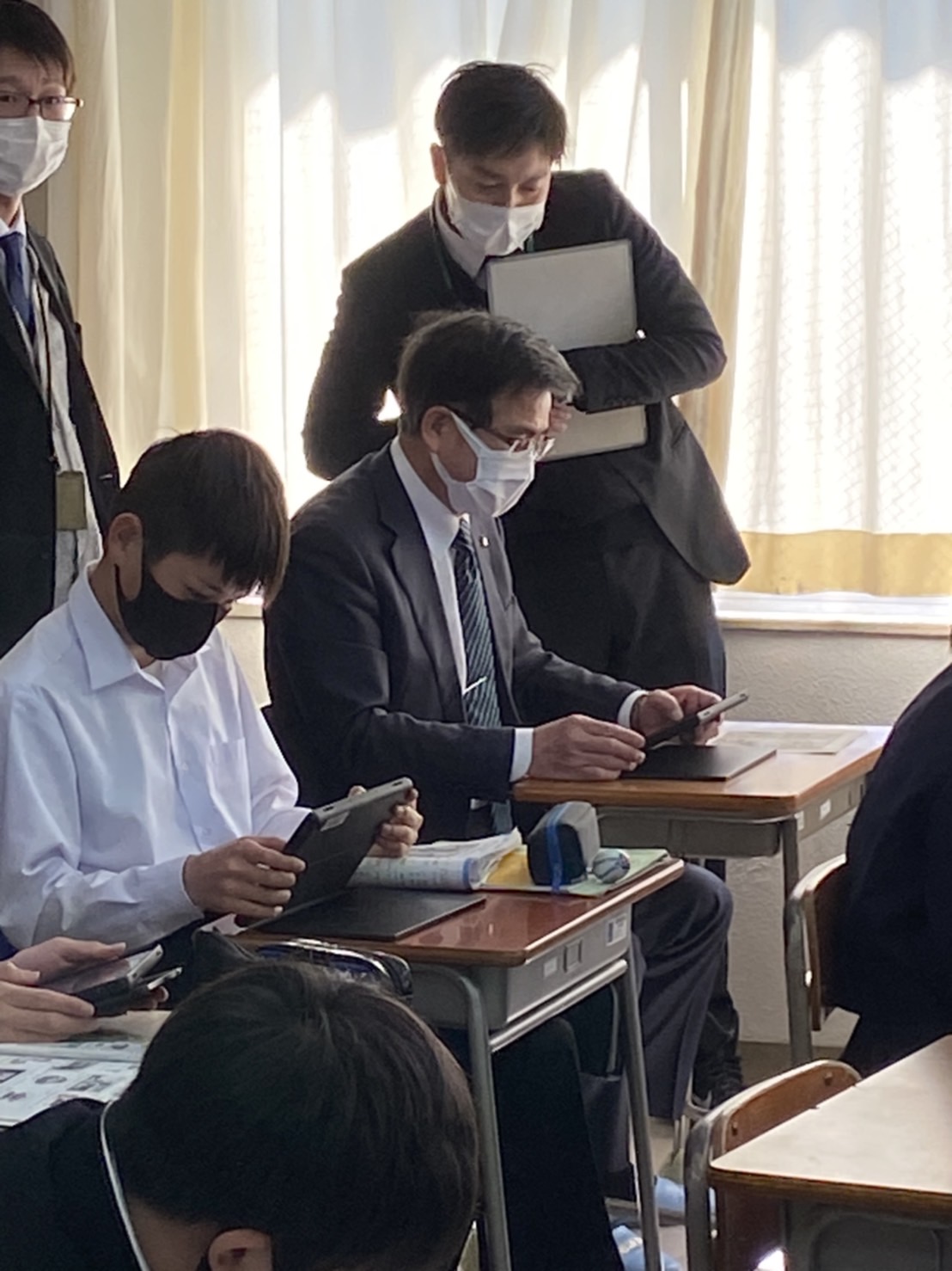 市長が生徒と一緒の教室の机に座り、それぞれタブレット端末を操作しており、実証授業している様子の写真