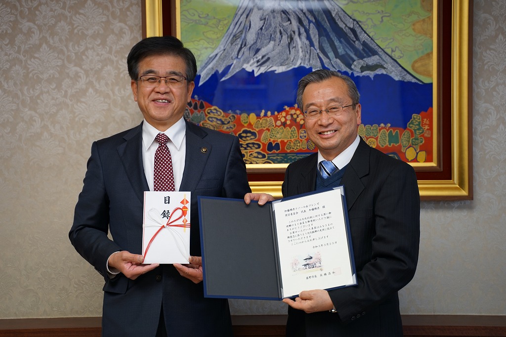 スーツを着た市長と男性が、記念品と感謝状を手に持ち笑顔で並んで写っている写真