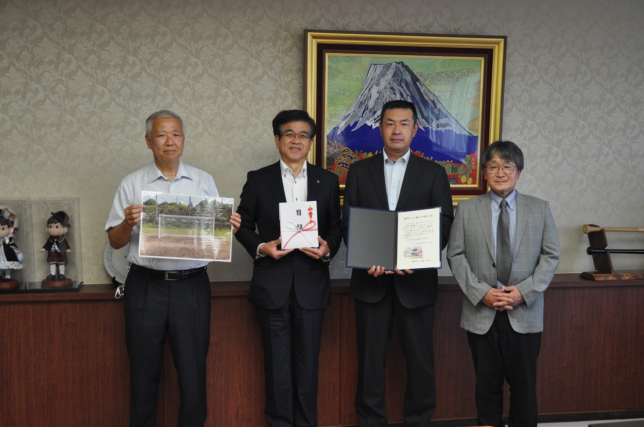 男性4人が並んでおり、感謝状や寄付の目録、工事完了後の写真などを手にしている集合写真