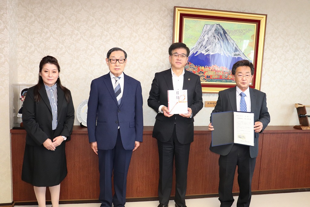 額縁に入った賞状と記念品を持った市長と3人の男女が横一列に並び記念撮影している写真