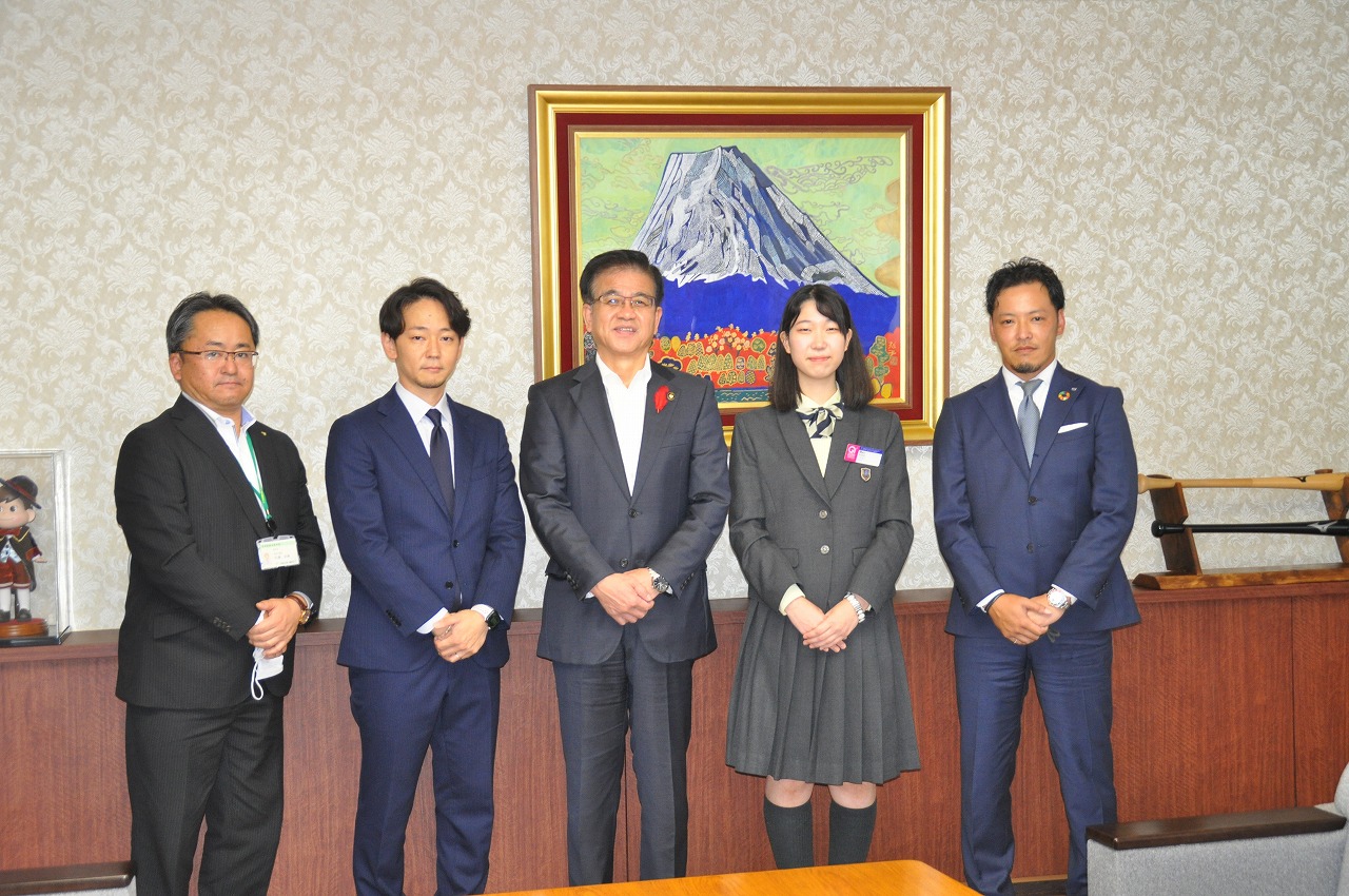 高橋市長を中心に制服姿の女性1名とスーツ姿の男性3名がカメラに向かって並び立ち、和やかな雰囲気で記念撮影をしている様子を捉えた写真