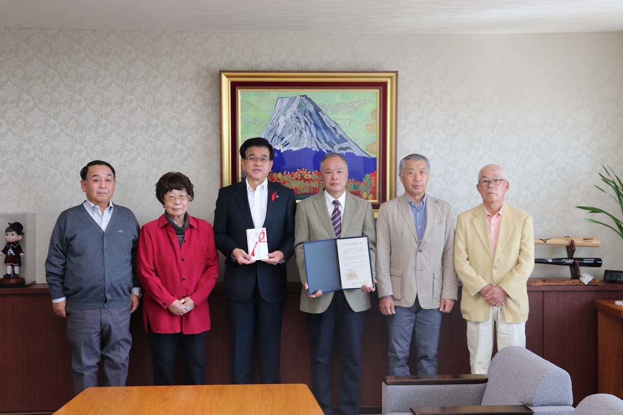 のし袋を持った高橋市長を中心に男女5名が横一列に並び、記念撮影をしている写真