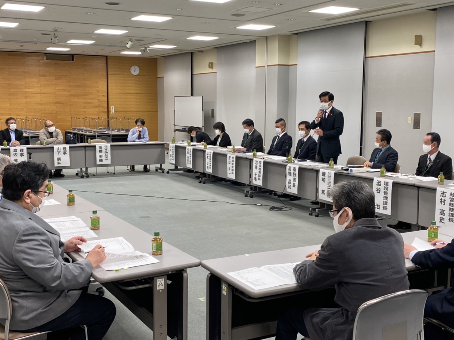 広い室内で複数の人々がテーブルを囲んで座っており、中央でマイクを持った高橋市長が発言している懇談会の様子を捉えた写真