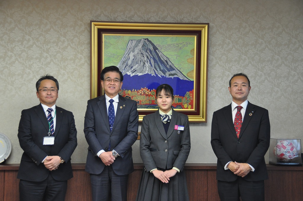 日本画の富士山の絵が飾られた壁を背景に、高橋市長を中心にスーツ姿の男性2名と制服姿の女性1名が並び、カメラに向かって静かに微笑んでいる集合写真