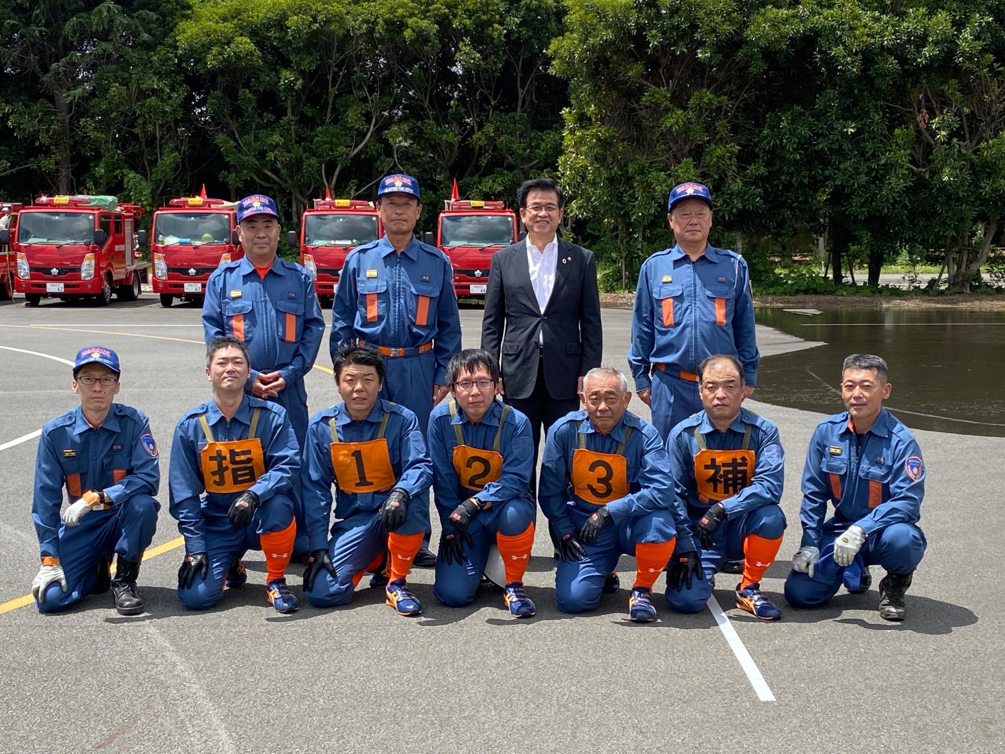 前列に7名の消防団員が座り、後列に3名の消防団員と高橋市長が並んで立ち、記念撮影をしている写真
