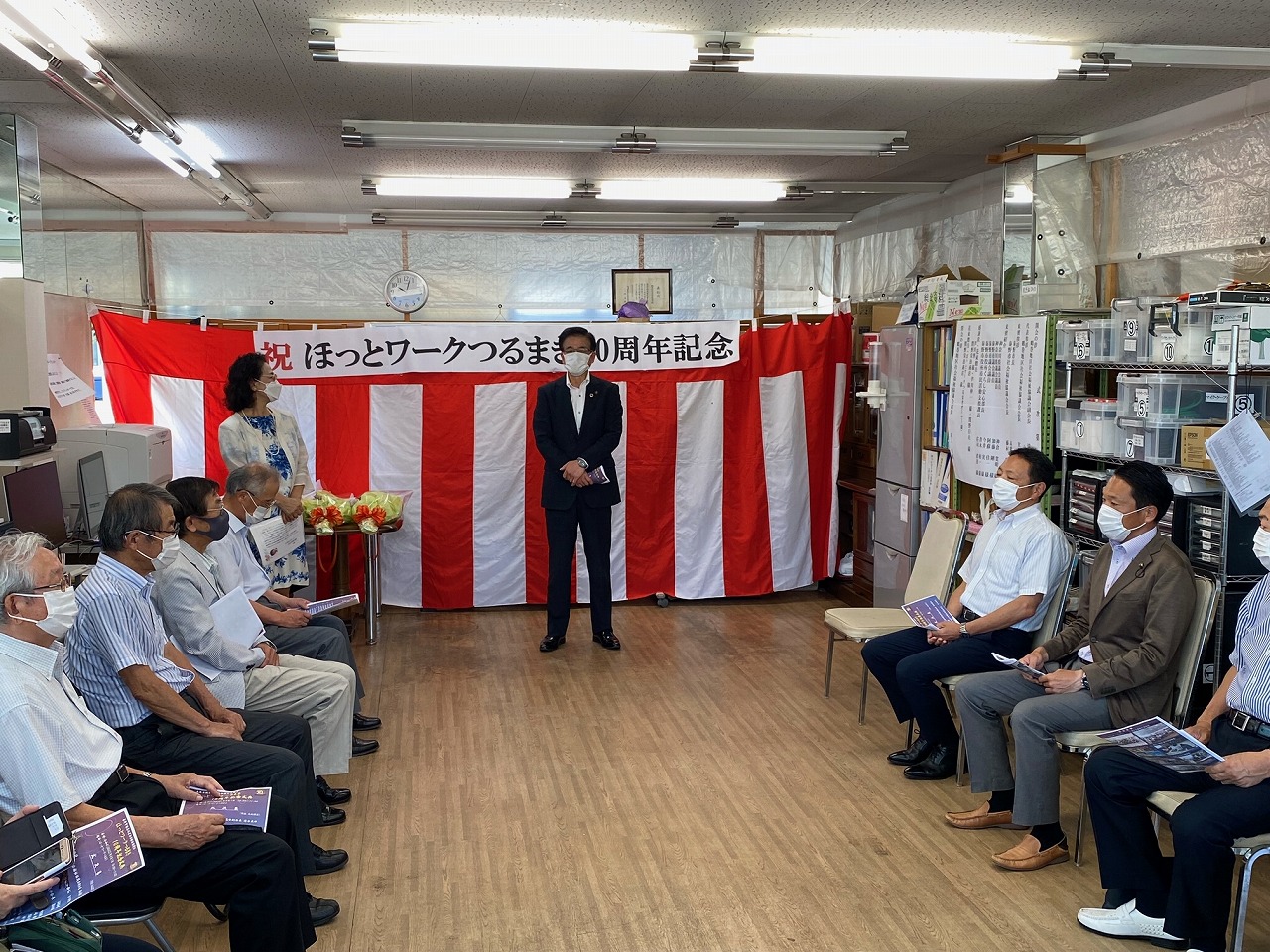 紅白幕を背景に市長が中央に立っており、左右に分かれた椅子に大勢の聴衆が着席している記念式典の様子の写真