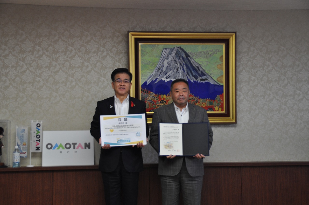 室内でスーツ姿の男性2人が賞状や目録を手に並んでおり、受領式の記念撮影の写真