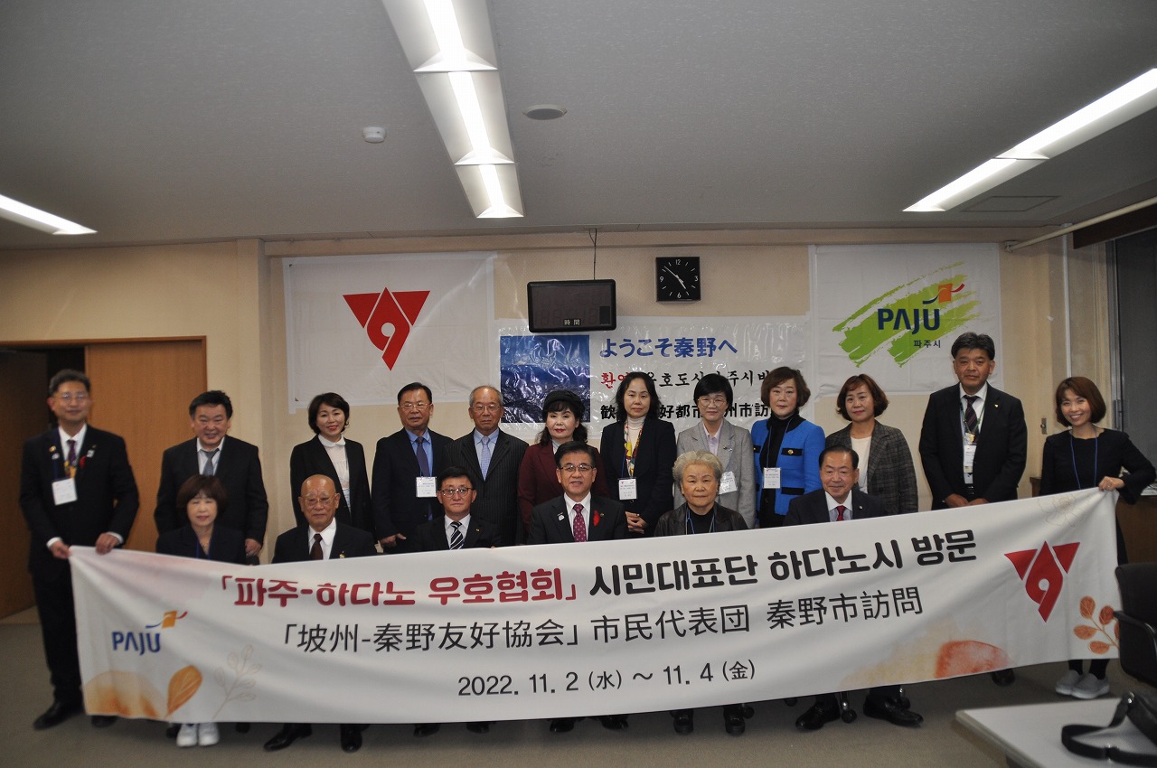 韓国の坡州市と秦野市の友好協会による交流イベントで、坡州 秦野友好協会 市民代表団 秦野市訪問と書かれた横断幕を持った日韓の代表団が笑顔で記念撮影をしている写真