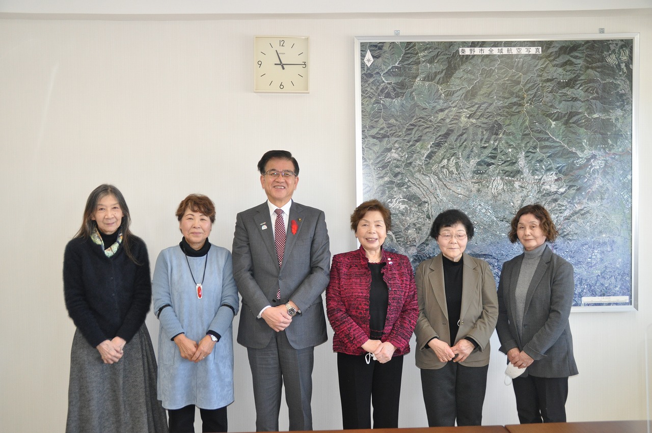 室内で市長を囲んで五人の女性が並んで記念撮影を行っている写真