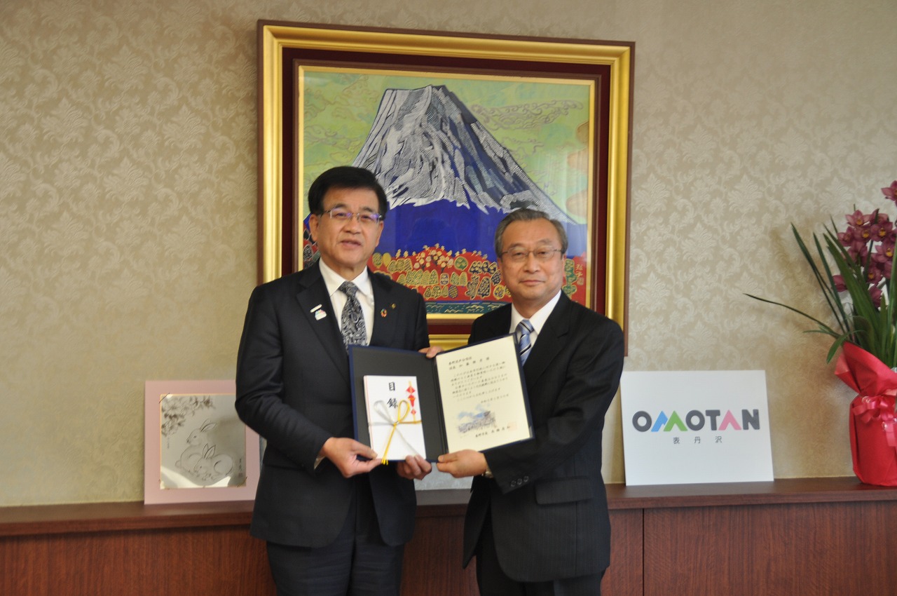 市長とスーツ姿の男性が並び、目録を一緒に持って記念撮影している写真