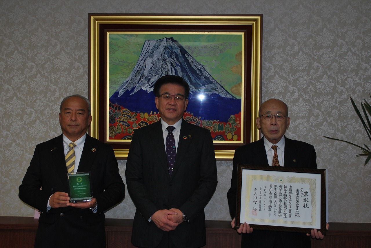 スーツ姿の市長と男性2人が並んでおり、左右の男性がそれぞれ表彰盾と賞状を手に記念撮影をしている様子の写真