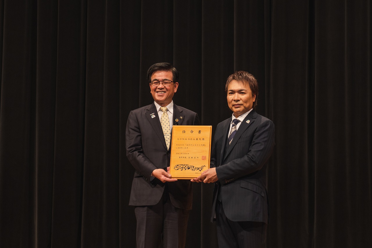 LUNA SEA・真矢さんと市長が任命書を二人で持ちながら記念撮影をしている写真