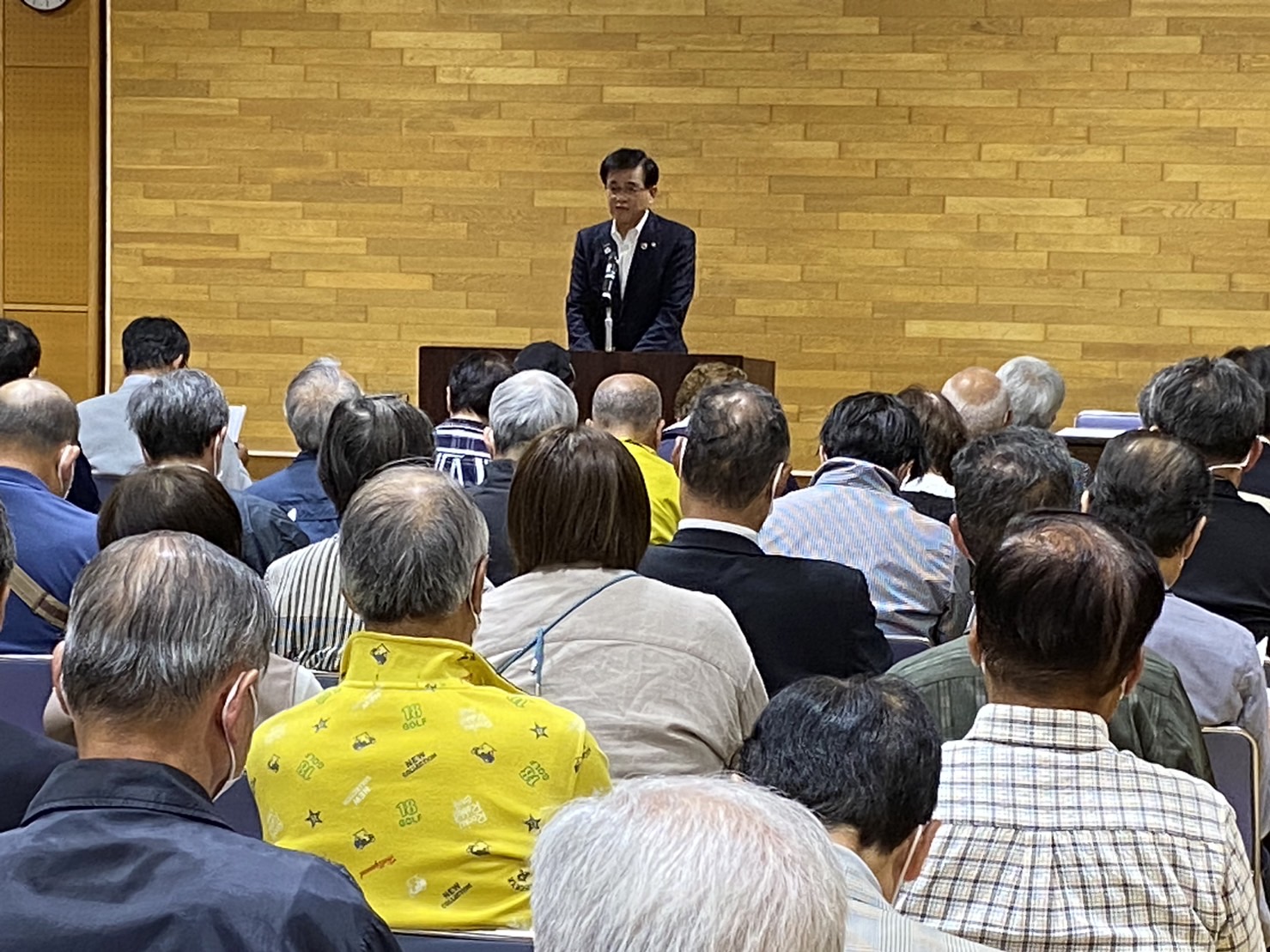 複数の方々が座っている中、前方の演台のマイクの前で市長が話ををしているまちづくり委員会定期総会の様子を写した写真