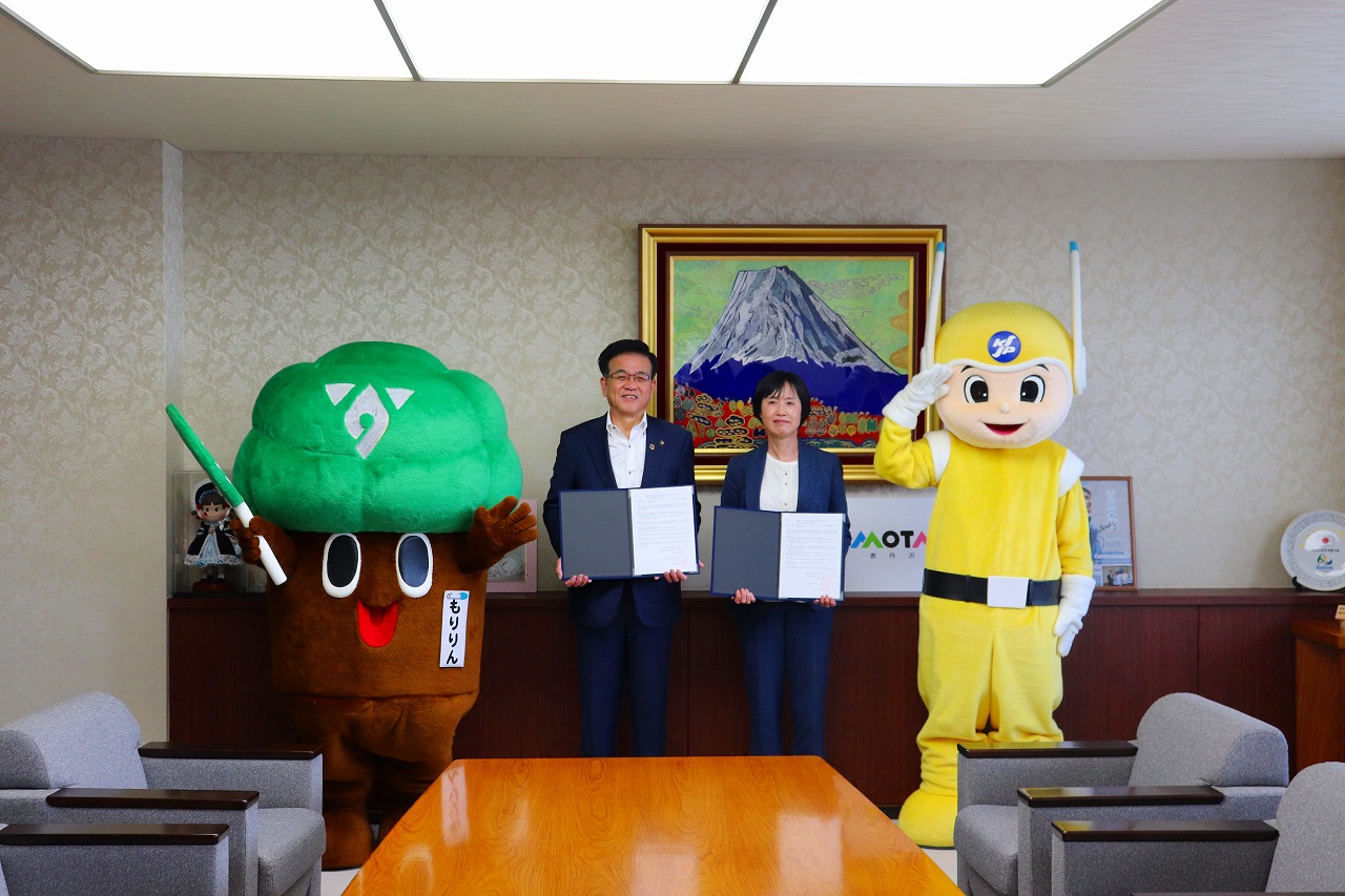 市長と女性が協定書を持ちながら女性の隣にはピーガルくん、男性の横にはもりりんのマスコットが並んで記念撮影をしている写真