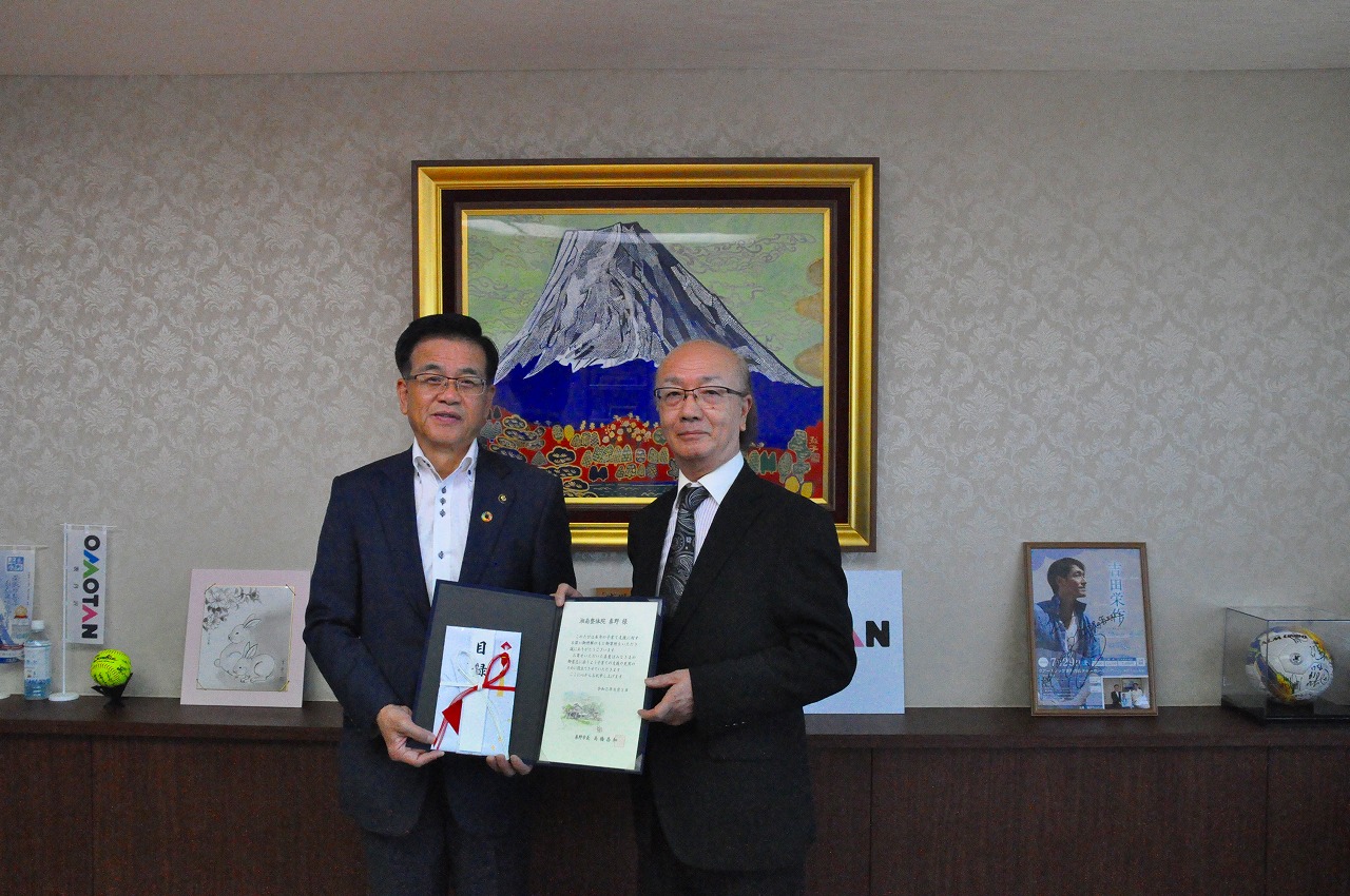 市長とスーツ姿の男性が2人並んで目録などをもちながら記念撮影をしている写真