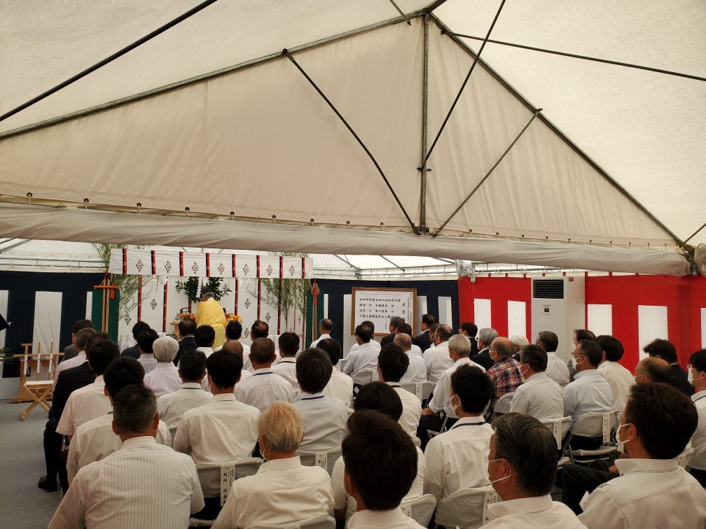 白いテントの下に設置された祭壇と、その前で神事に参列している多くの人々の後姿を捉えた写真