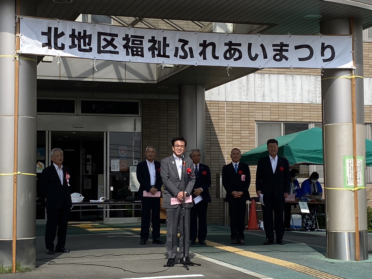 「北地区福祉ふれあいまつり」と書かれた横断幕の下で、マイクに向かってスピーチをする高橋市長と、他の複数の関係者が立っている写真