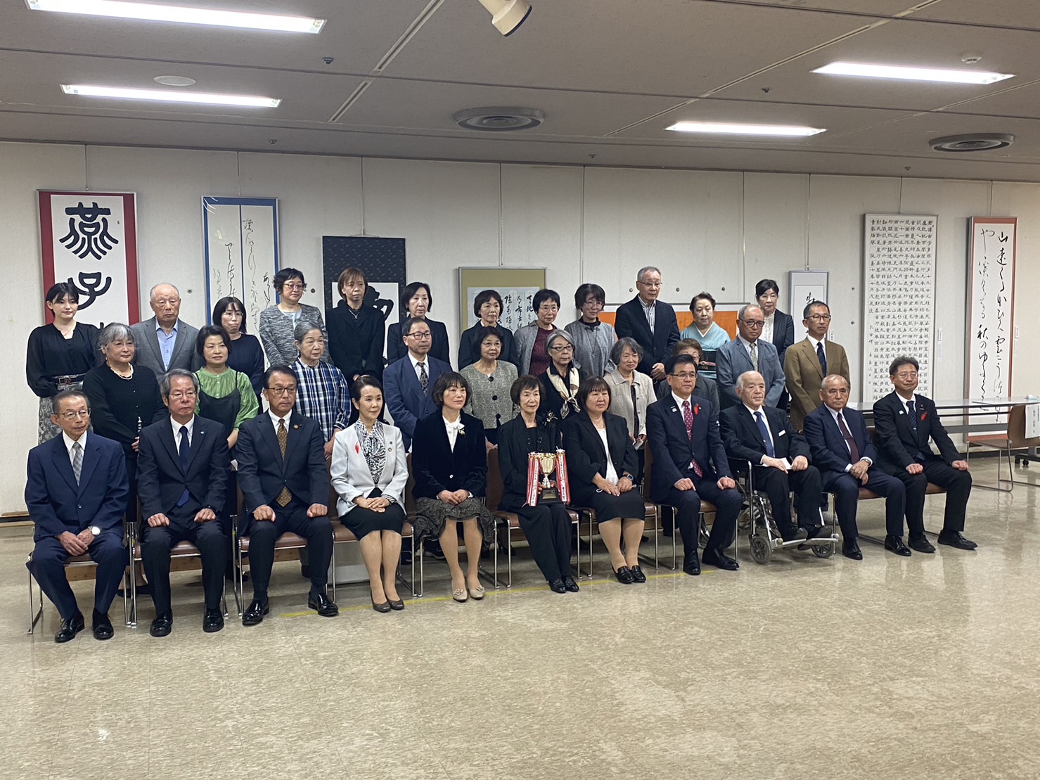 受賞しトロフィーを持った女性や市長が中央に座り、関係者の方々が集まって3列に並び写っている第53回秦野市展・書道の部表彰式の記念写真