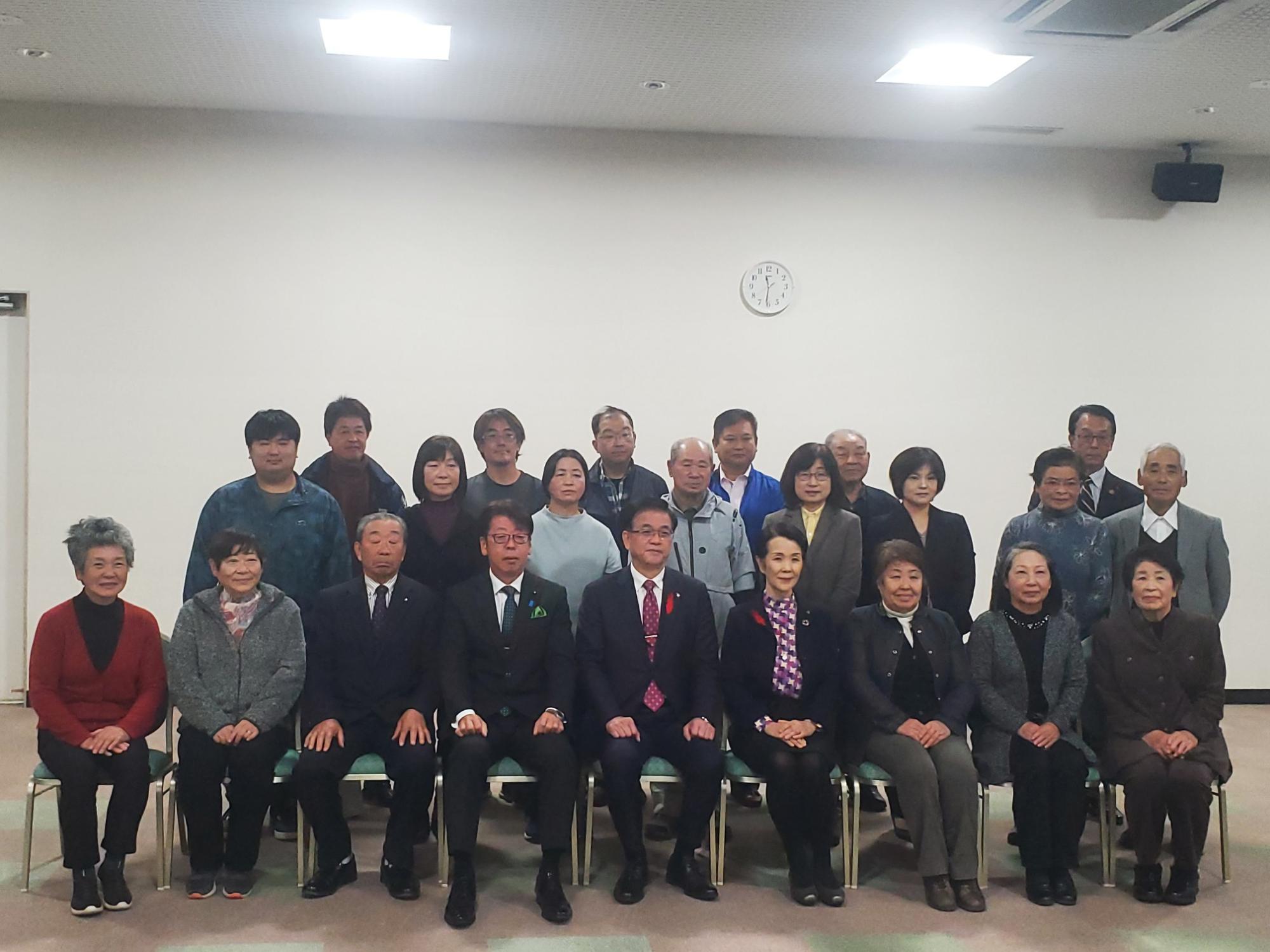 市長が中央の席に座り、関係者の方々が3列に並んで写っている記念写真