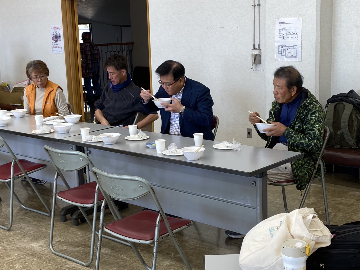 長机の前に座った市長と関係者の方々が、出来上がった料理の試食をしている様子の写真