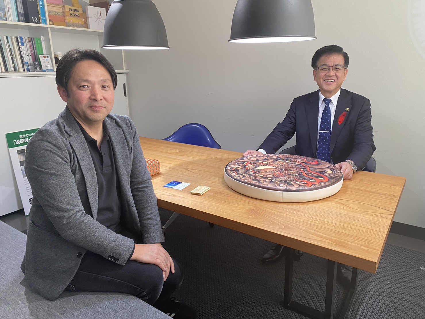 作品がおかれたテーブルを挟んで向かいあって座り、カメラに笑顔を向けている藤元晶扇さんと高橋市長の写真