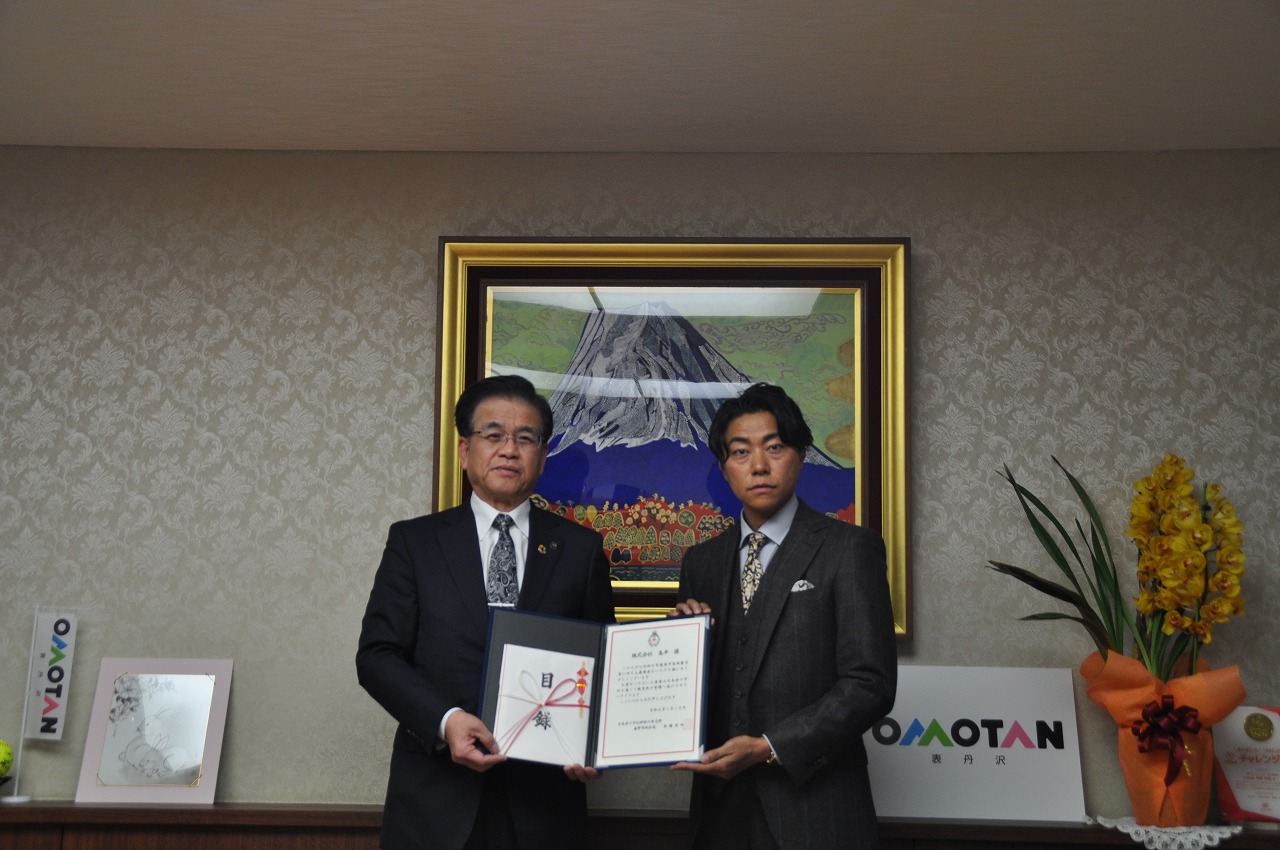 市長と鈴木代表取締役が一緒に目録などを持ち記念撮影している写真