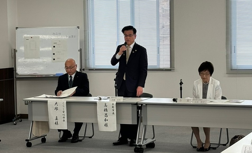 設置されたテーブルに関係者が座る中央に市長が立ちマイクを使って話をしている様子の写真