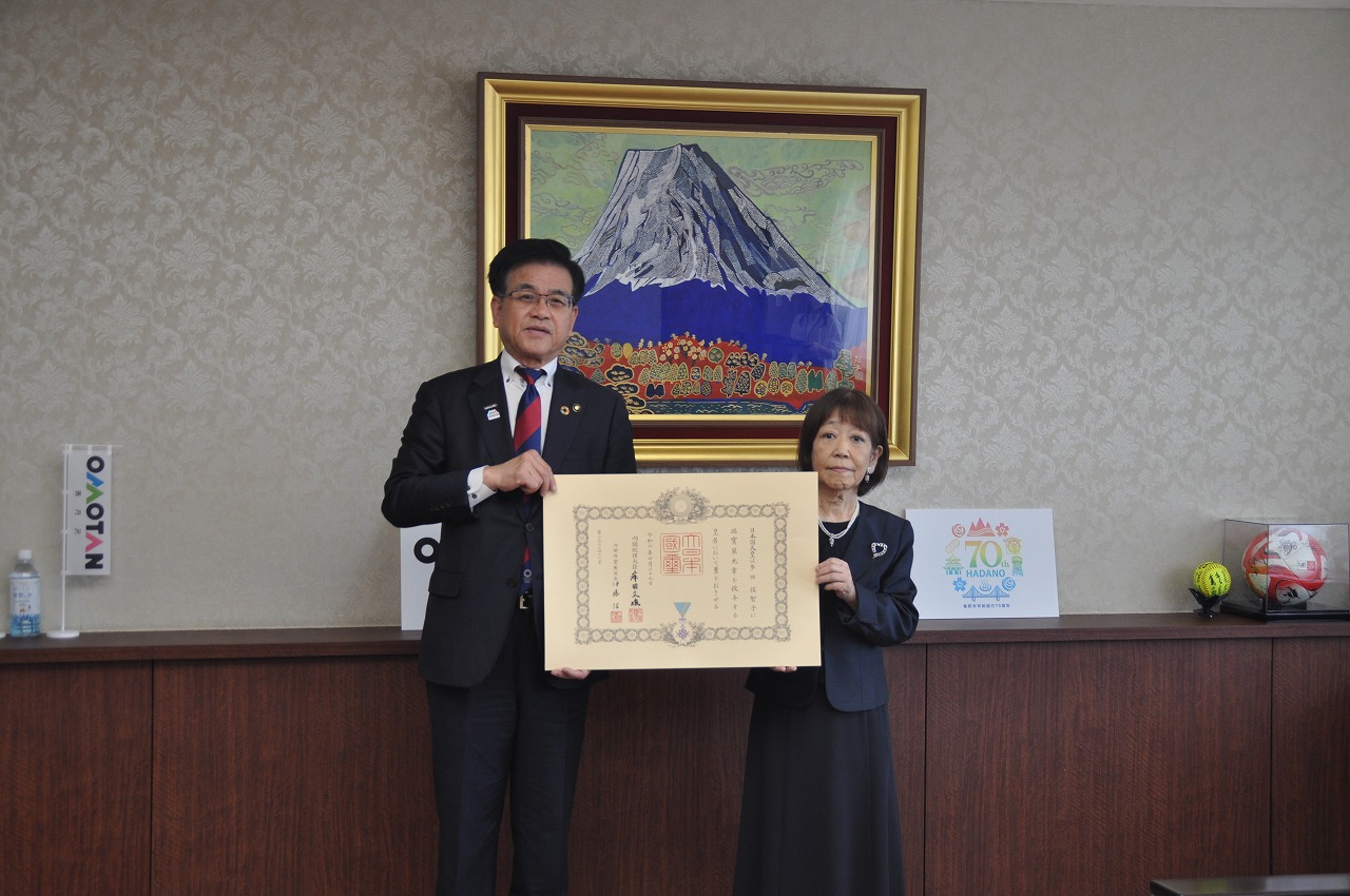 表彰状を手にして並ぶスーツ姿の市長と黒い服を着た多田佐智子さんが記念撮影をしている感謝状贈呈の写真