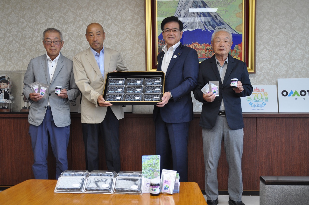 市長と男性3人がブルーベリーのパックやジャムを手に持ち、カメラに向かって立っている集合写真