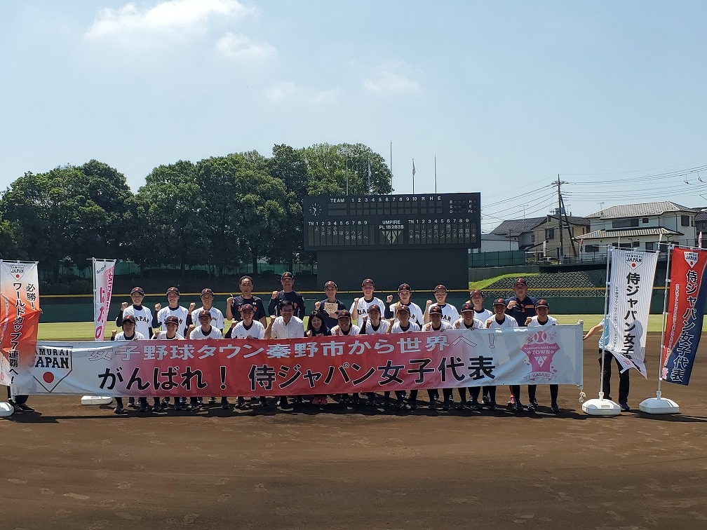 女子野球チーム全員と関係者が『がんばれ！侍ジャパン女子代表』と書かれた横断幕を持ち、集合写真を撮っている写真