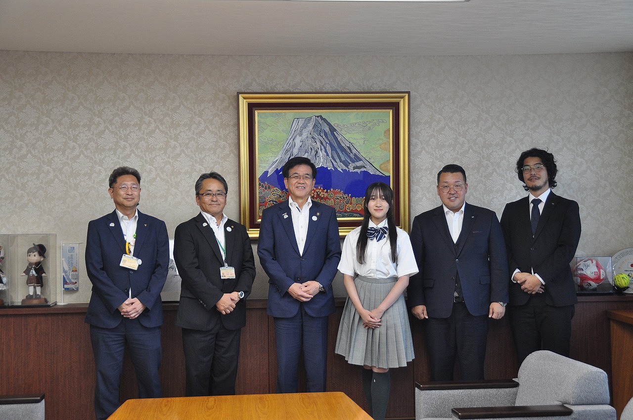 富士山の絵が飾られた応接室で、制服姿の伊東とスーツ姿の市長と男性が横一列に並んで笑顔で記念撮影している様子の写真