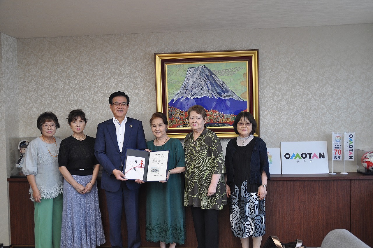 富士山の絵が飾られた応接室で、スーツ姿の市長と5人の女性が表彰状を持って笑顔で記念撮影している様子の写真