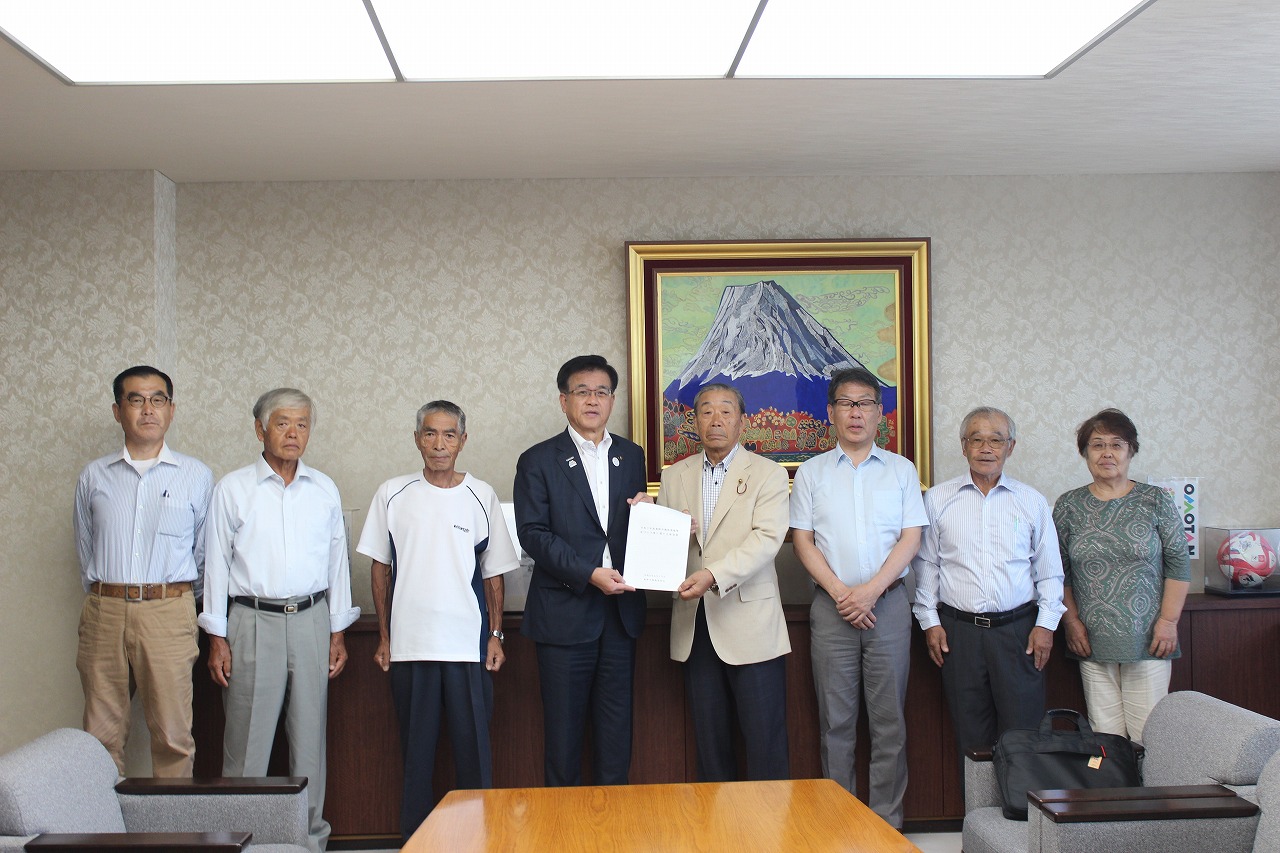 富士山の絵が飾られた室内で、市長と関係者が並び、地域団体の代表が要望書を市長に手渡して記念撮影をしている様子の写真