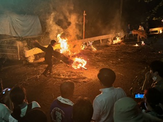 男性が火のついたたいまつを振り回す、迫力ある火祭りの写真