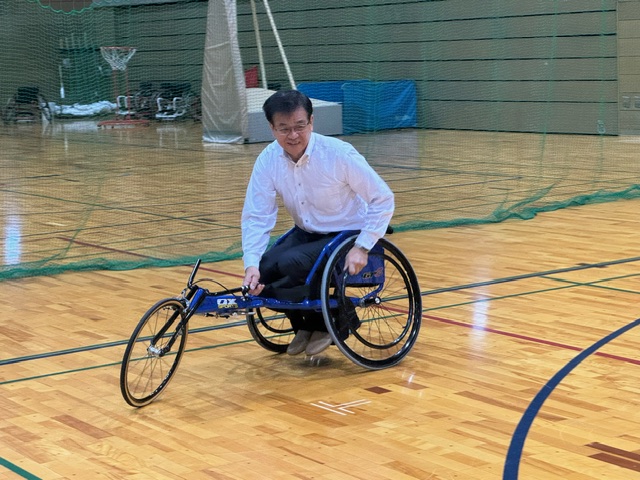 体育館で、競技用車いすに乗り笑顔で写っている市長の写真