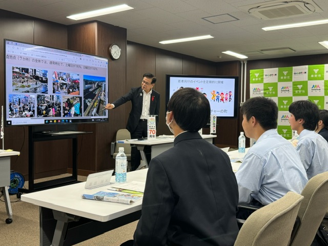 プロジェクターで資料を映し出し、真剣な表情で話す市長を、数名の学生が熱心に聞いている意見交換会の写真