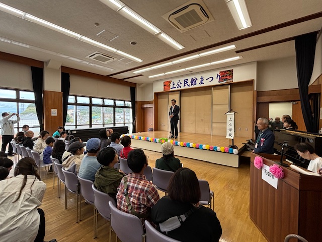 まつりの会場で、舞台の上でマイクを手に話す市長を、たくさんの来場者が座って聞いているイベント風景の写真