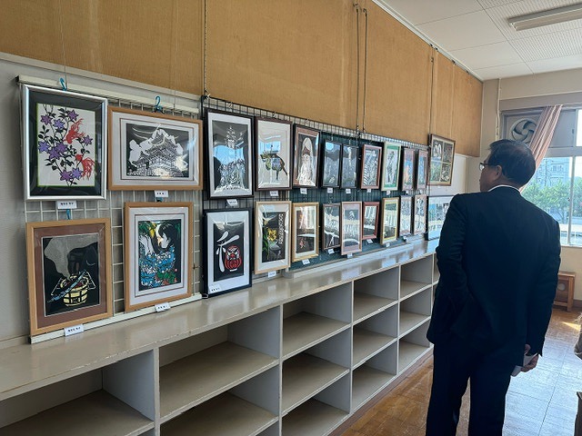 壁に掲示された切り絵などの作品を鑑賞している高橋市長の後ろ姿の写真
