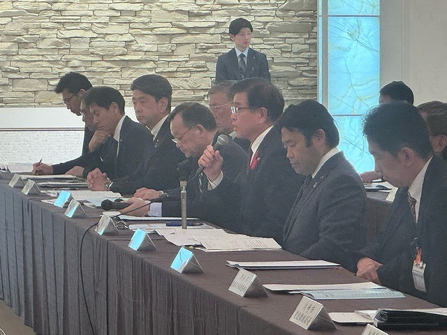 たくさんの男性が長机の席に着席する中、中央あたりに座った高橋市長が、マイクを持って話をしている写真