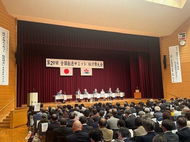 「第29回 全国報徳サミット 桜川市大会」の横断幕が掲げられた舞台上に設けられた長机に数名が着席し、広いホールいっぱいに多くの聴衆が座っている会場の様子の写真