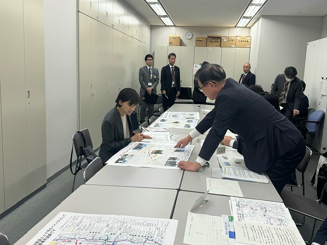 席を立った高橋市長が、女性の近くにある資料を手で示している様子の写真