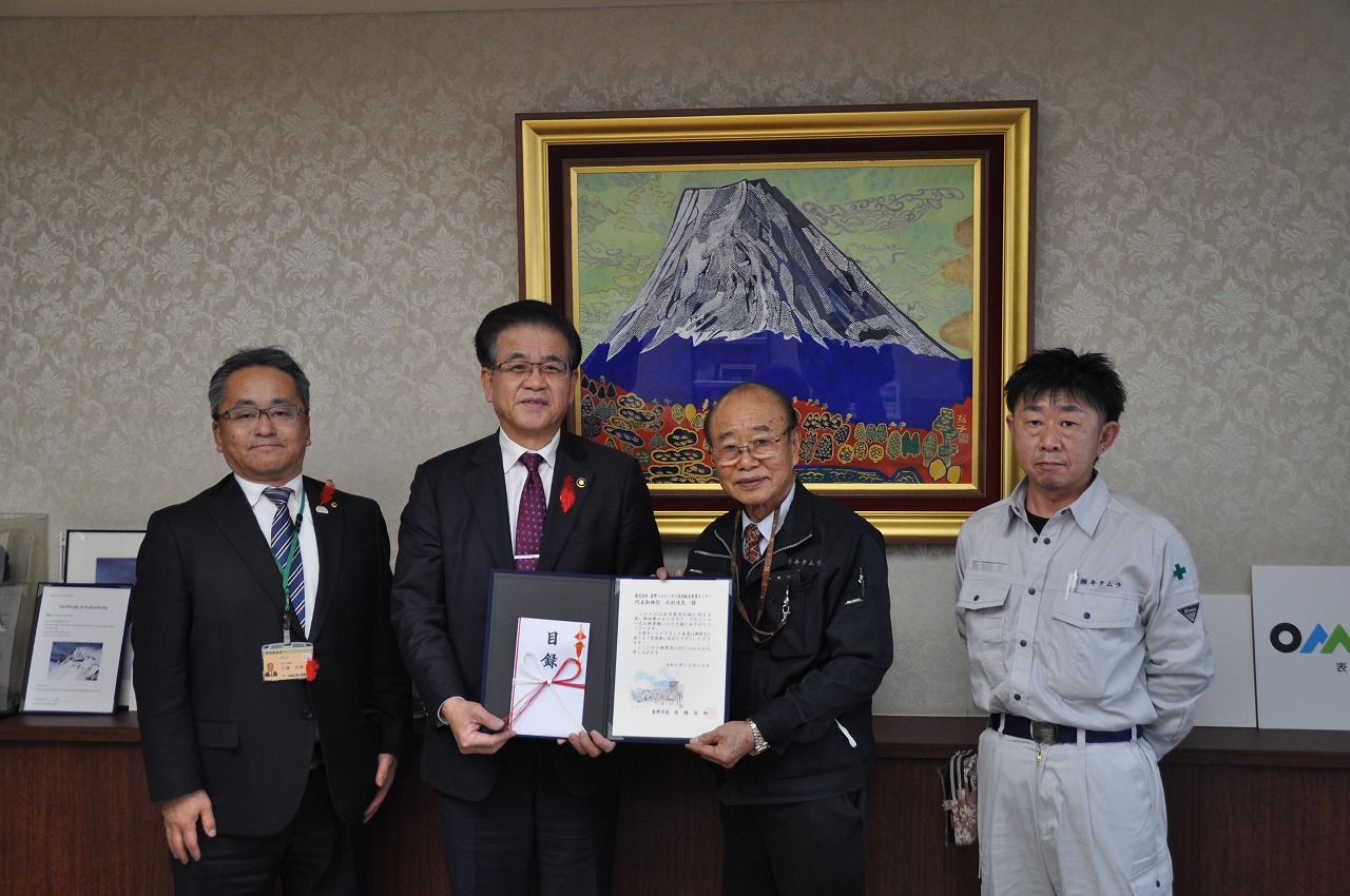 市長を含めた4人の男性が並んでおり、そのうちの2人が目録などを両手で持っている集合写真