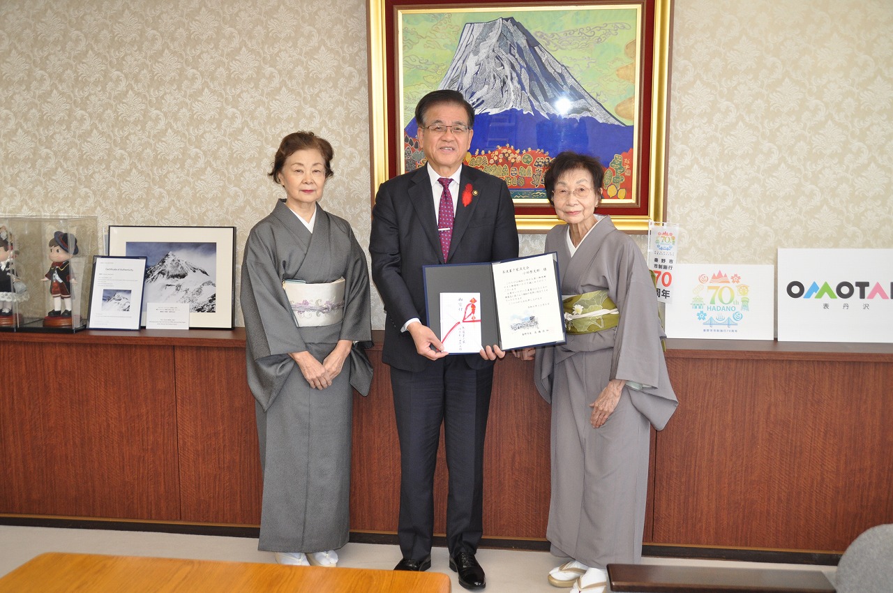 市長が着物姿の二人の女性と一緒に、目録などを手に記念撮影をしている写真