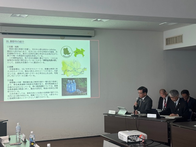 中央のモニターに資料が映し出され、マイクを持った市長が座って説明をしている写真