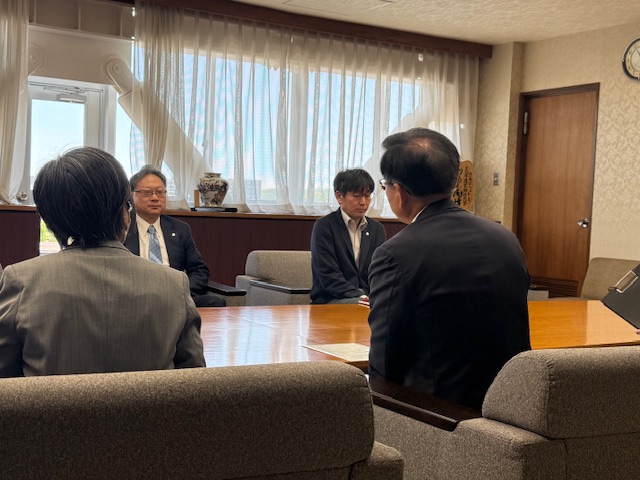 対面に座っている山下理事長に話しかけている市長の後姿を写した写真