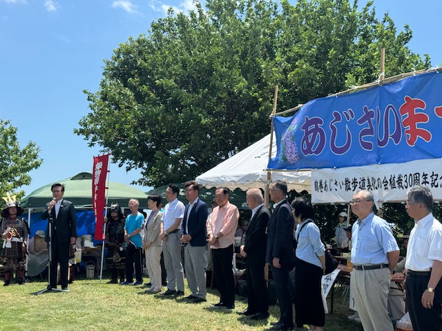 パネルに展示された絵手紙や俳句、絵画をスーツ姿の市長と男性が鑑賞している、屋内展示会の様子を捉えた写真