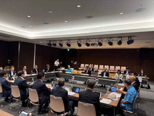 ロの字型に設置された長机を囲んで多くの関係者が着席し、中央の席に座ったスーツ姿の市長がマイクを持って話している、室内で行われている会議の様子の写真