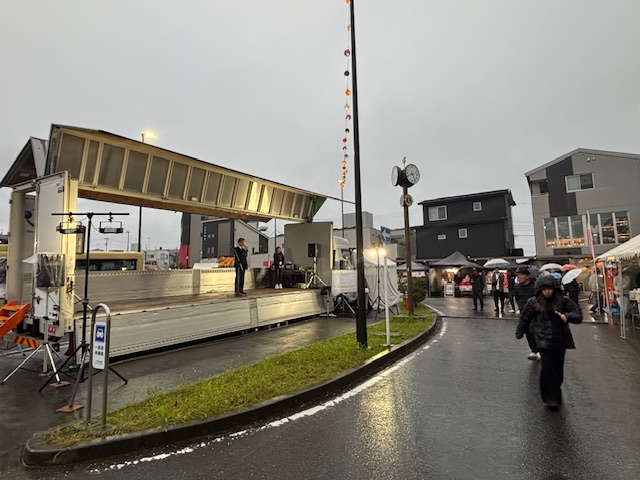 大きなトラックの荷台のステージで挨拶する市長を遠くから撮った写真