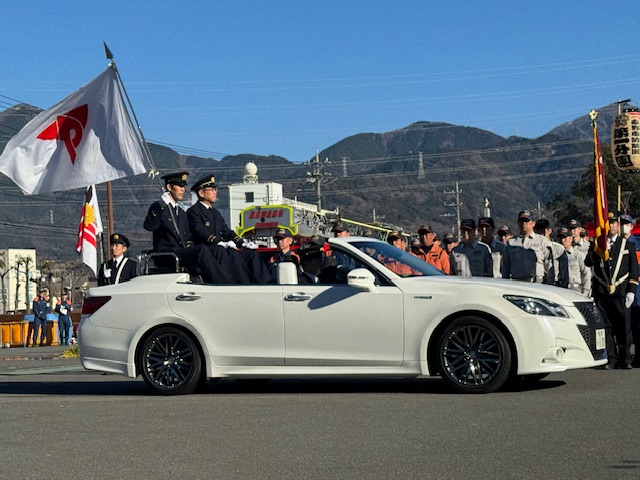 白いオープンカーに乗ってパレードをする消防の制服を着た市長