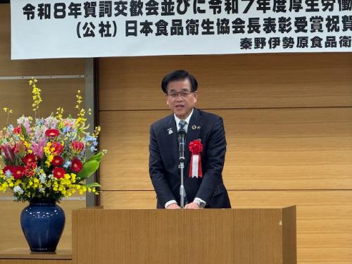 演台の後ろに立って挨拶する市長。左側には花が飾られている。